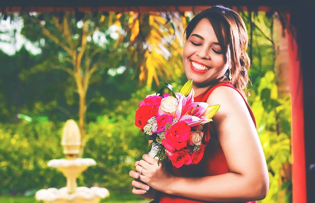 mujer sonriente con vestido rojo y ramo de flores